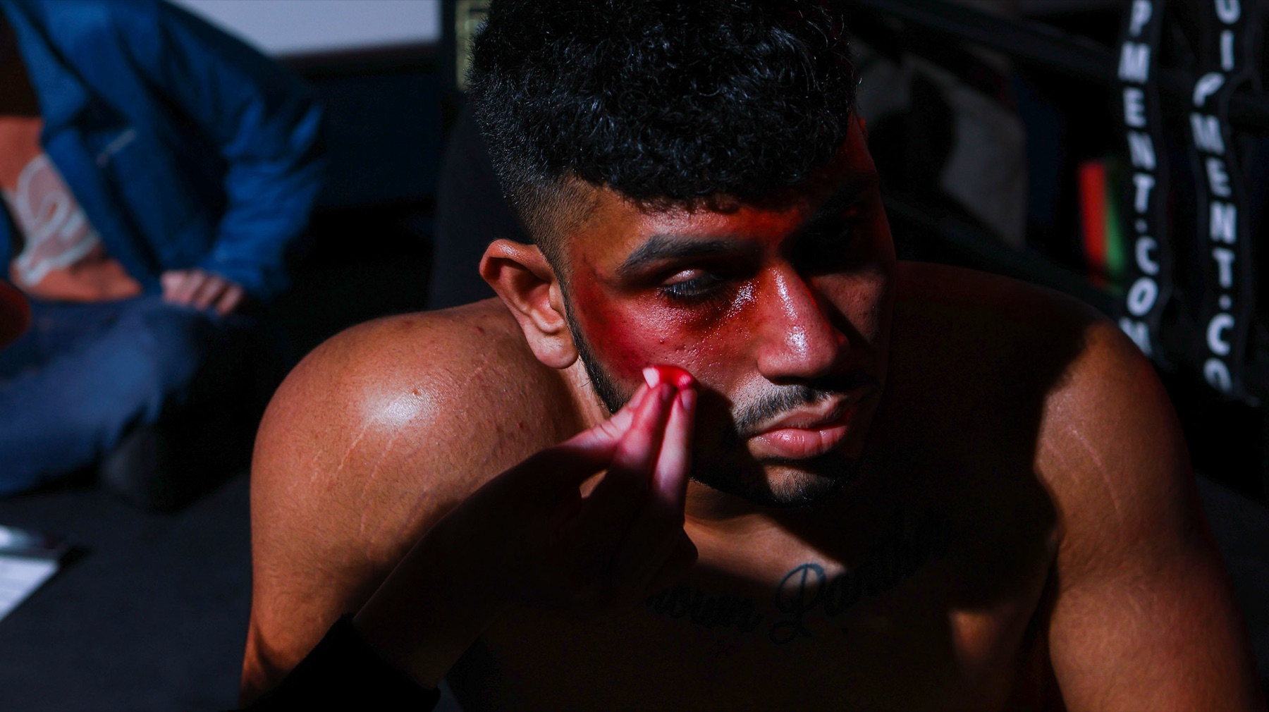 Sree as Benji, shirtless and bruised, touching his bleeding lip