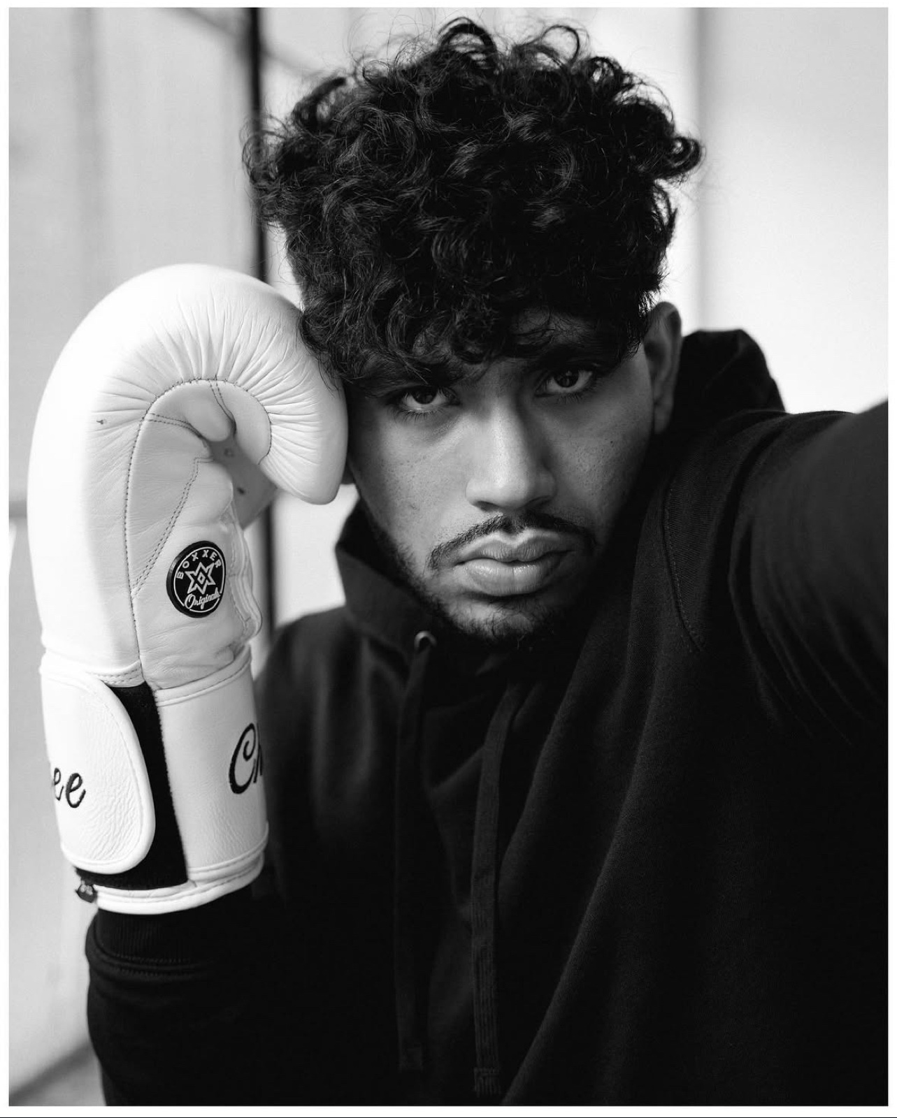 Sree pressing a white boxing glove to the side of his face, staring ahead