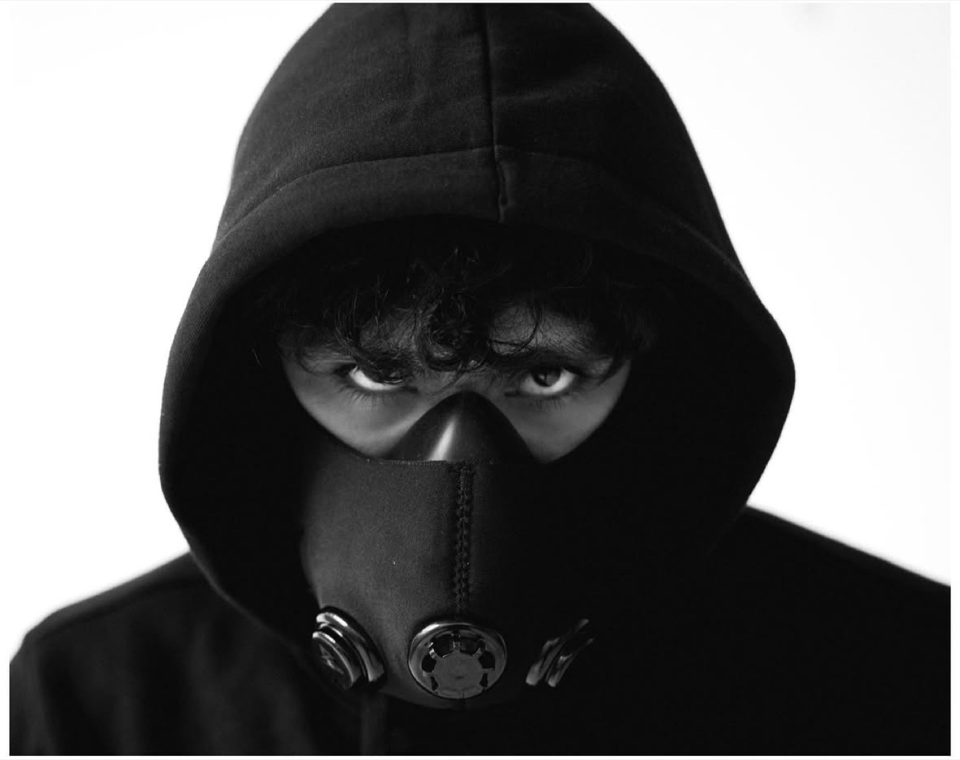Sree in a black hood and training mask, only his eyes showing, staring into the camera
