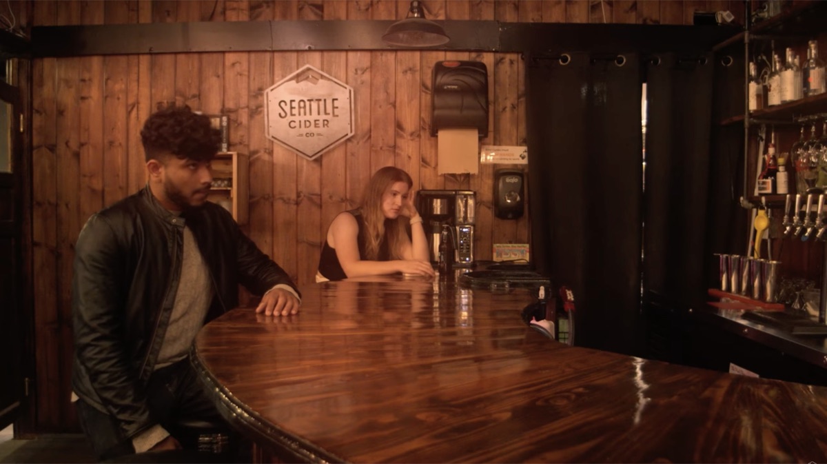Sree as Sebastian at a bar, turned away from the bartender