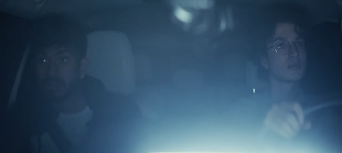 Sree as Ben in a car at night with the driver beside him